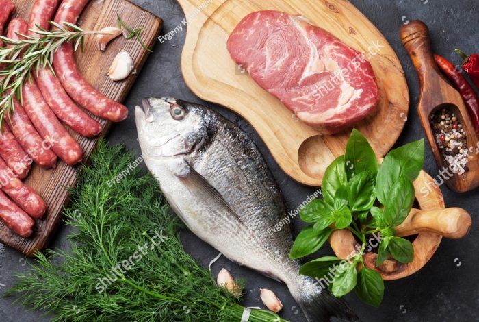 stock-photo-sausages-fish-meat-and-ingredients-cooking-top-view-on-stone-table-472568125